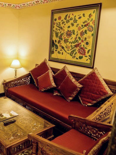 Traditional carved wooden seating area in a hotel room at Fort Chandragupt Hotel Jaipur